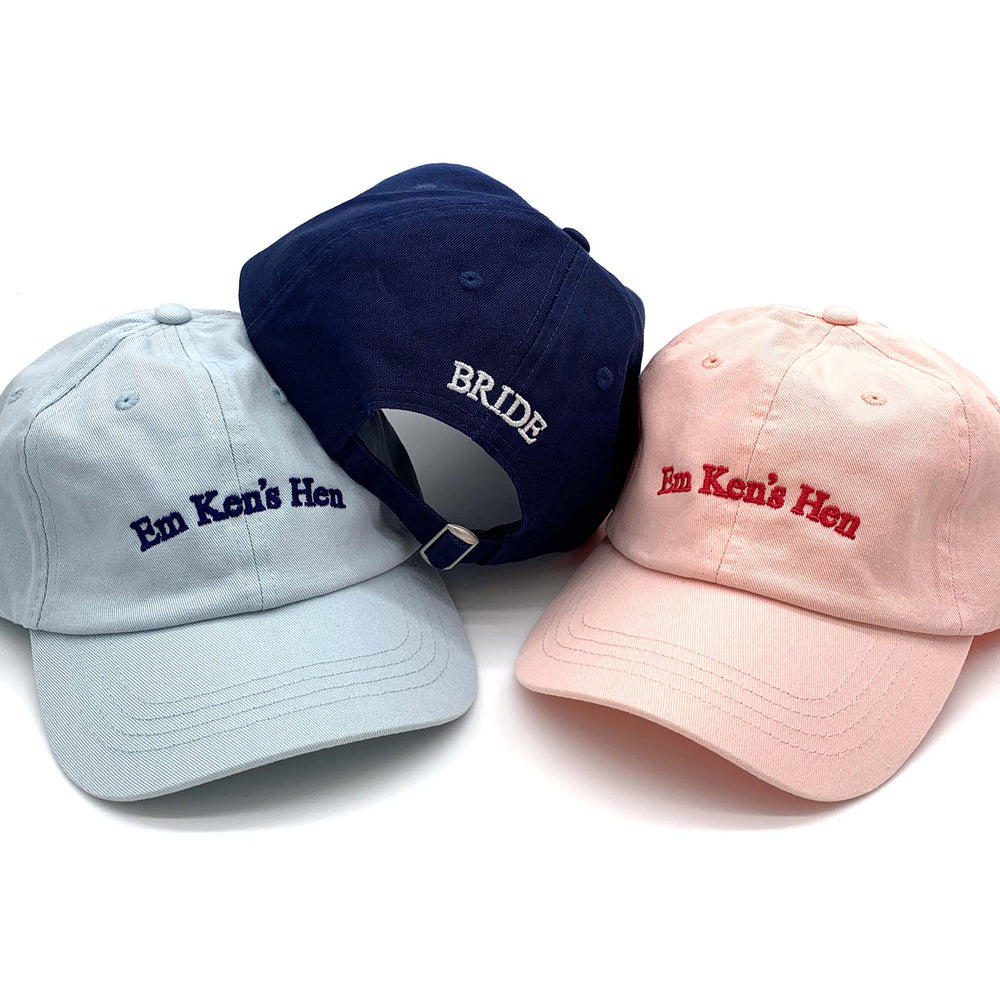 three caps in pale blue, navy and pink, embroidered for a hen do. The navy cap has Bride on the back.